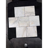 Six square white calacatta verde royale marble 12x12 tiles with subtle gray veining arranged in a cross pattern on black surface