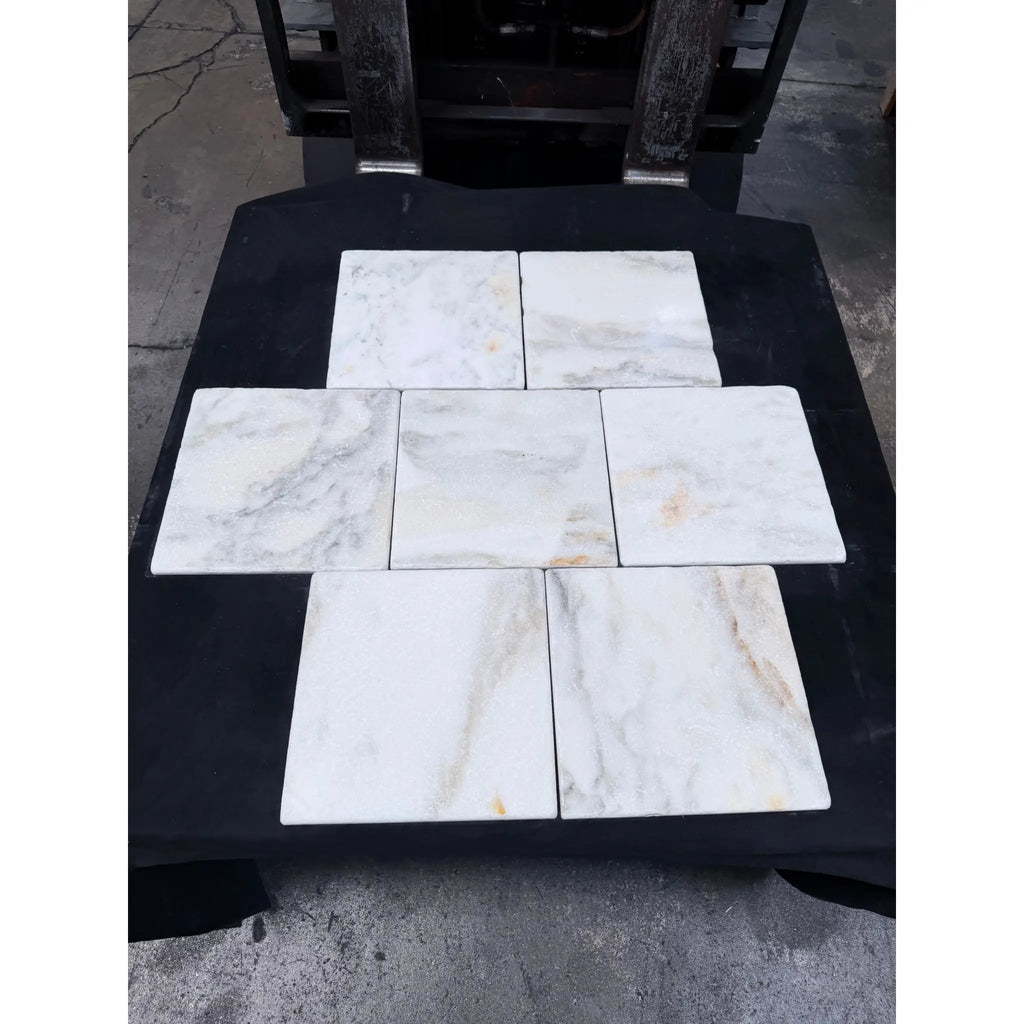 Six square white calacatta verde royale marble 12x12 tiles with subtle gray and beige veining arranged in a cross pattern
