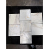 Calacatta verde royale marble 12x12 tile tumbled in white with subtle gray and beige veining arranged in a cross pattern