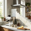 Stainless steel espresso machine with sleek modern design and control dials beside calacatta verde royale marble 2x2 mosaic tile