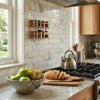 A copper two-tier spice rack with glass jars displayed on a calacatta verde royale marble 2x4 brick mosaic tile surface