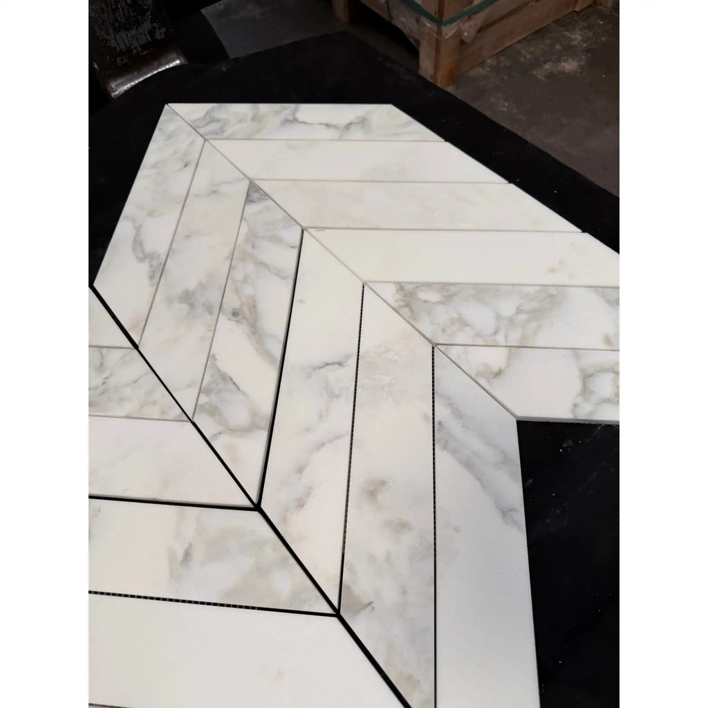 White marble calacatta verde royale 3x12 tiles with gray veining in a chevron mosaic pattern with black grout lines