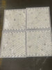 Four sheets of white penny round mosaic tiles wrapped in plastic for Calacatta Oliva Marble