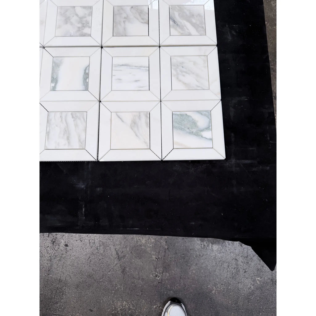 White marble-effect square tiles with gray veining arranged in a grid pattern in Calacatta Verde Royale mosaic