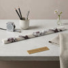 A sleek cylindrical calacatta viola imperiale marble pencil liner trim with white base and dark purple veining