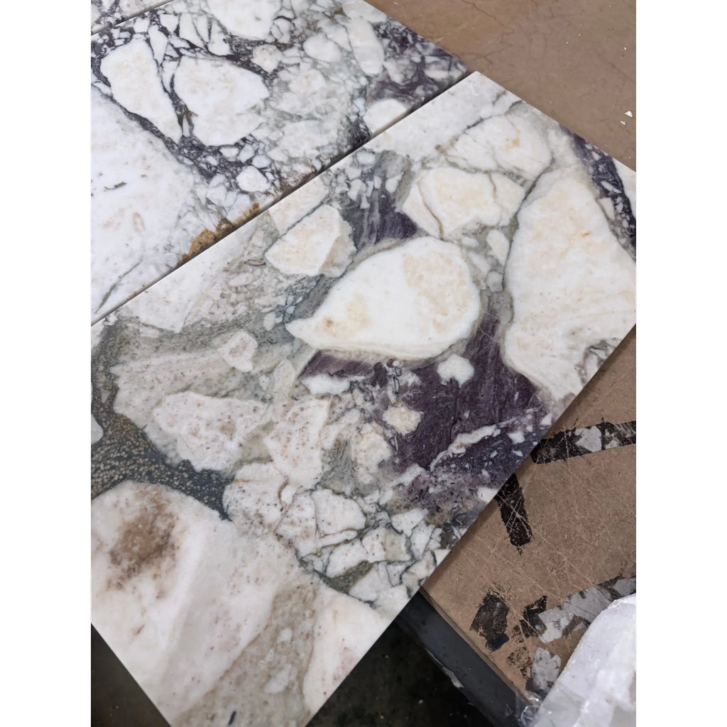Calacatta Viola Imperiale marble slabs in white and dark gray with natural veined pattern, 12x24 polished-honed
