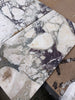 Calacatta Viola Imperiale marble slabs in white and dark gray with natural veined pattern, 12x24 polished-honed