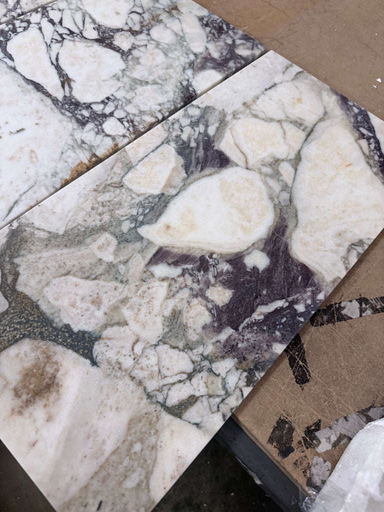 Calacatta Viola Imperiale marble slabs in white and dark gray with natural veined pattern, 12x24 polished-honed