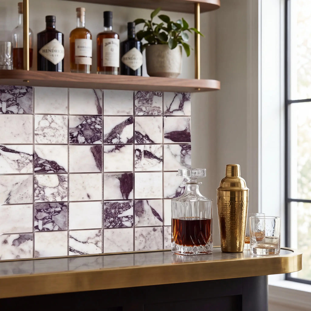 A sleek gold-toned hammered cocktail shaker with polished cap displayed on calacatta viola imperiale marble 2x2 mosaic