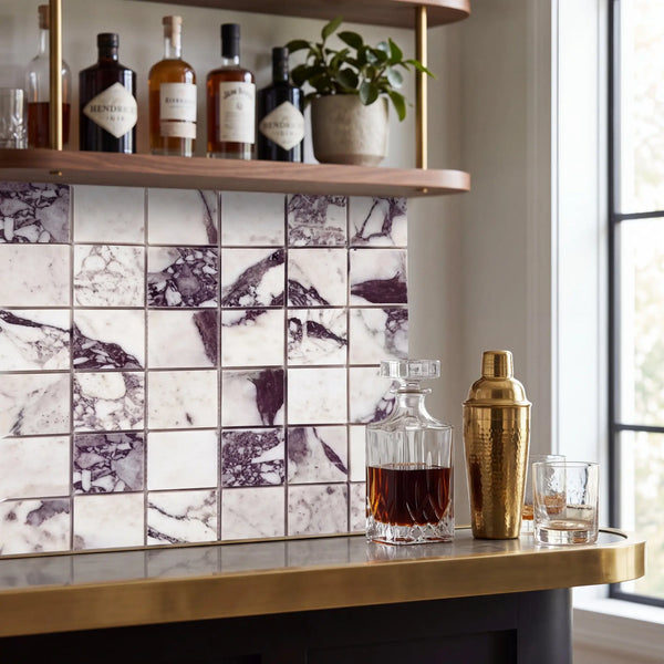 A sleek gold-toned hammered cocktail shaker with polished cap displayed on calacatta viola imperiale marble 2x2 mosaic