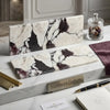 Two rectangular calacatta viola imperiale marble slabs with white base and purple black veining on matching surface
