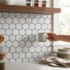 A matte gray ceramic mug with a simple modern design displayed on carrara white 1 inch hexagon mosaic marble tile polished or honed