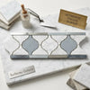 Elegant carrara white mosaic tile with gray quatrefoil pattern and polished marble inlays for luxury border use