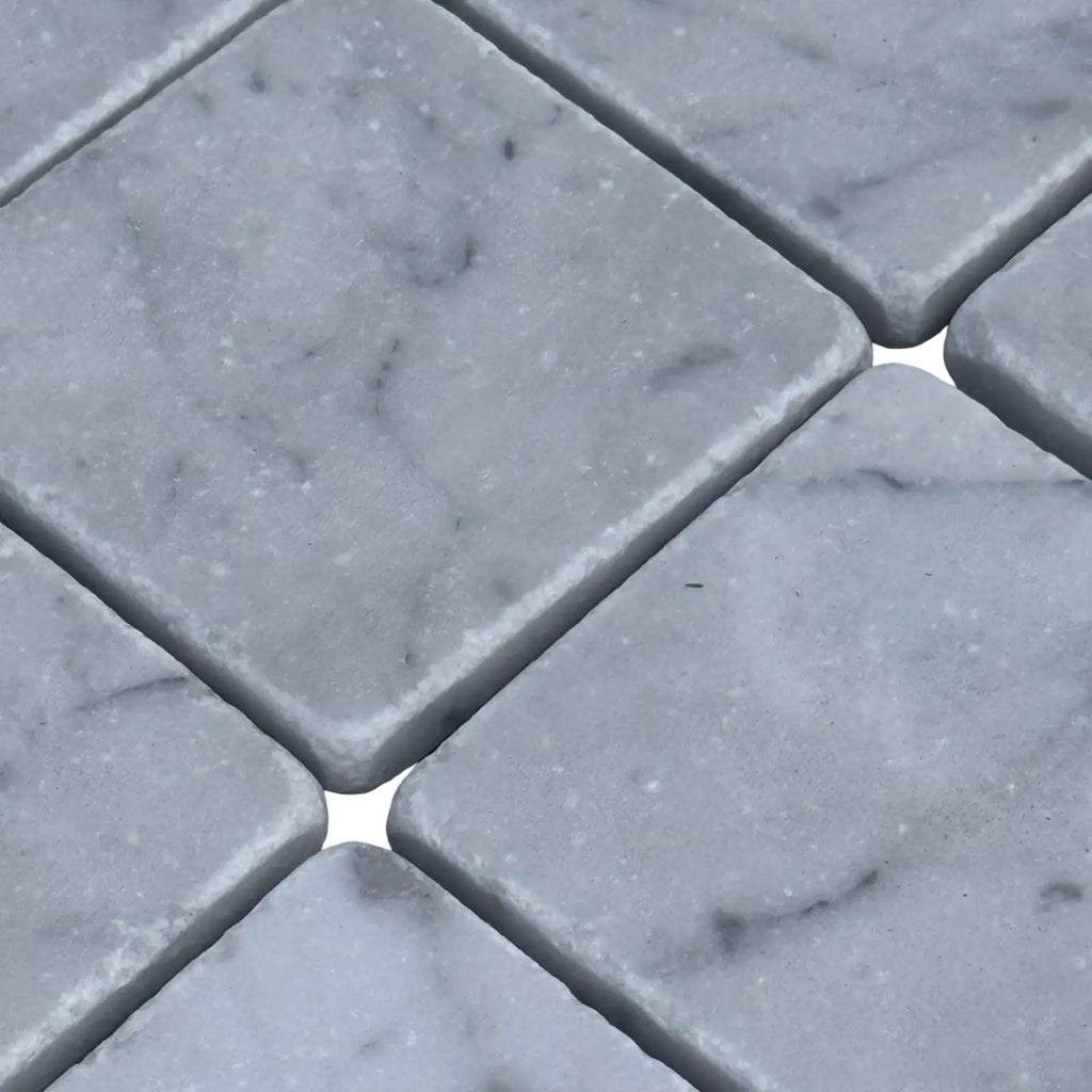 Diamond-shaped white marble mosaic tiles with gray veining in Carrara White 3X3 Tumbled design