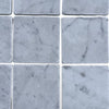 Light gray marble tiles with subtle dark veining from Carrara White 3X3 Tumbled collection