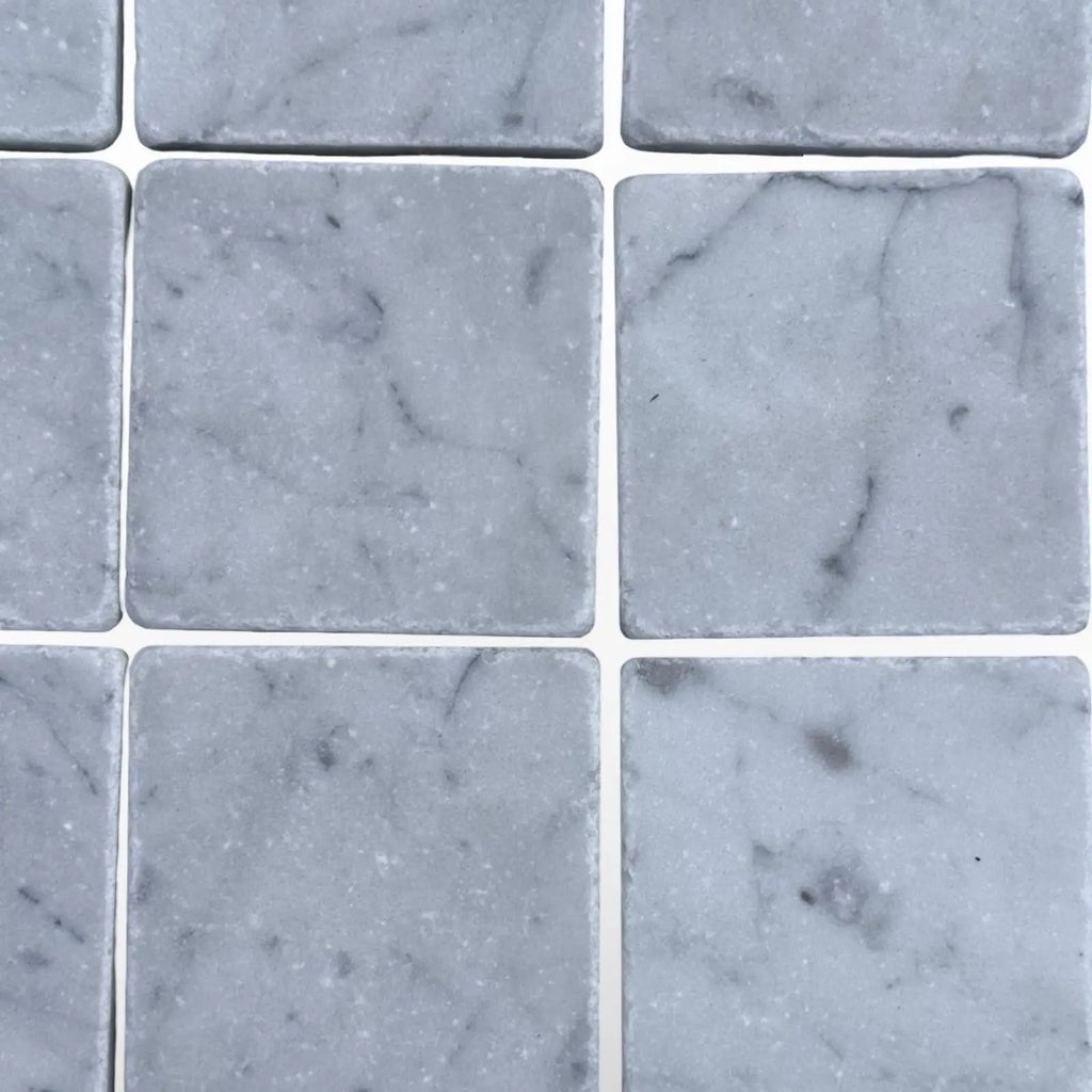Light gray marble tiles with subtle dark veining from Carrara White 3X3 Tumbled collection
