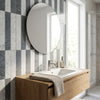 Round silver-framed mirror above wooden vanity sink with Carrara White Bardiglio Imperiale 3 x 12 field tile backdrop