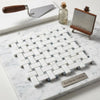 Carrara white basketweave mosaic marble tile in white and gray with blue-gray accents displayed on matching marble surface