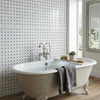 Antique cream-colored clawfoot bathtub with ornate silver faucet on carrara white basketweave mosaic marble tile