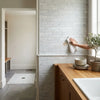 A white cloth towel wiping a polished carrara white manhattan random strip mosaic marble tile wall