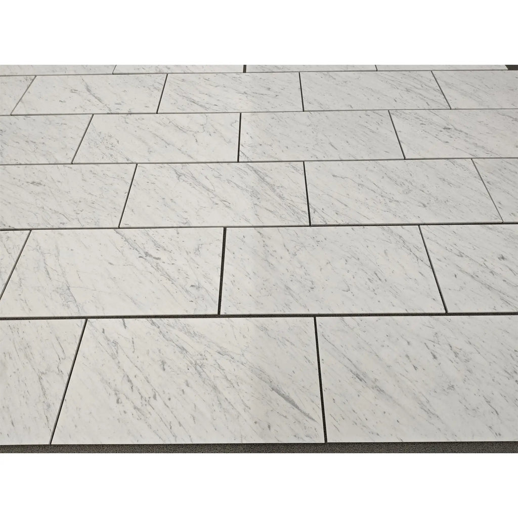 Carrara white marble 18x36 polished tiles with subtle gray veining arranged in a staggered pattern