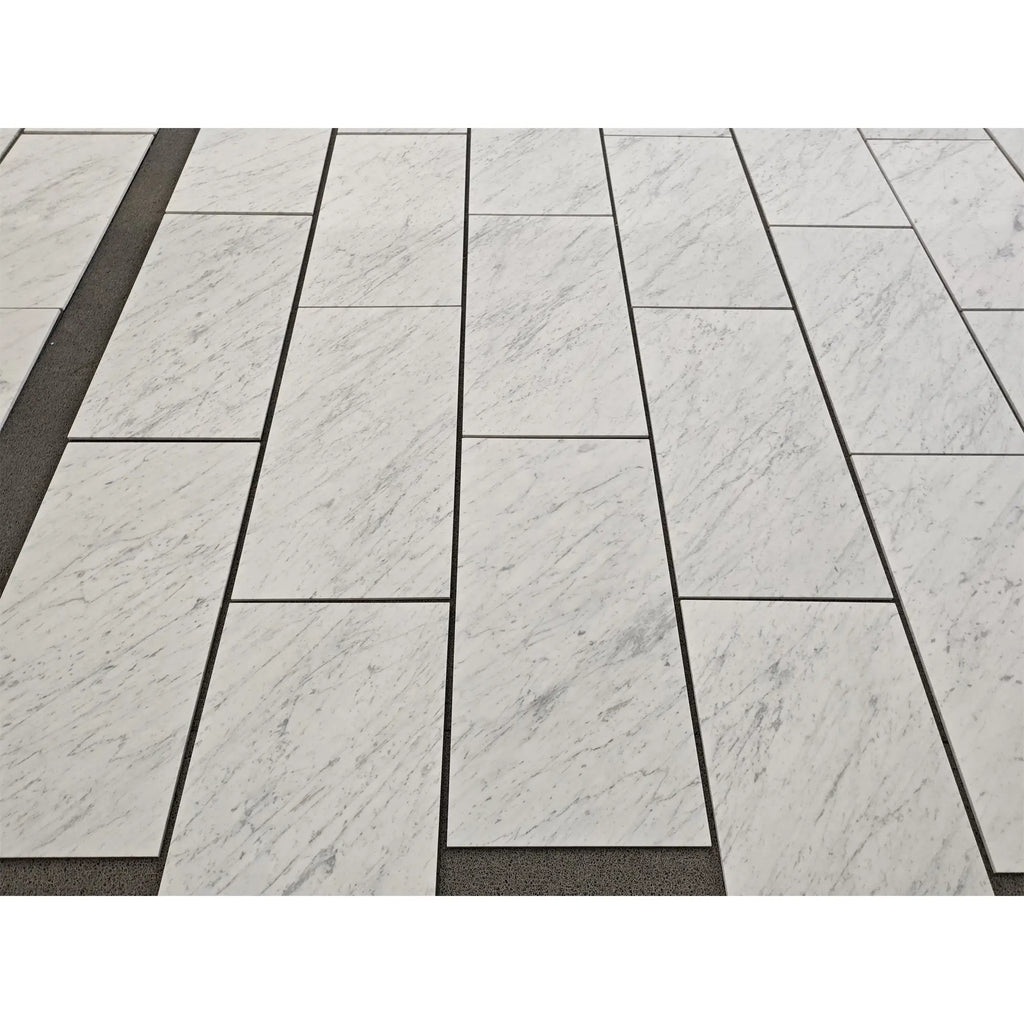 White marble tiles with subtle gray veining in a staggered pattern carrara white marble 18x36 polished or honed