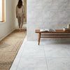 A minimalist wooden bench with a smooth light brown finish and tapered legs placed on Carrara white marble 24x24 floor