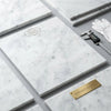Carrara white marble 24x24 polished slab with subtle gray veining and a nearby gold plaque engraved surfaces galore