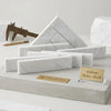 Carrara white marble 2x8 polished or honed rectangular blocks with subtle gray veining displayed on concrete base