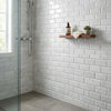 A sleek minimalist wooden shelf with a natural finish paired with carrara white marble 4x12 deep-beveled polished-honed tiles