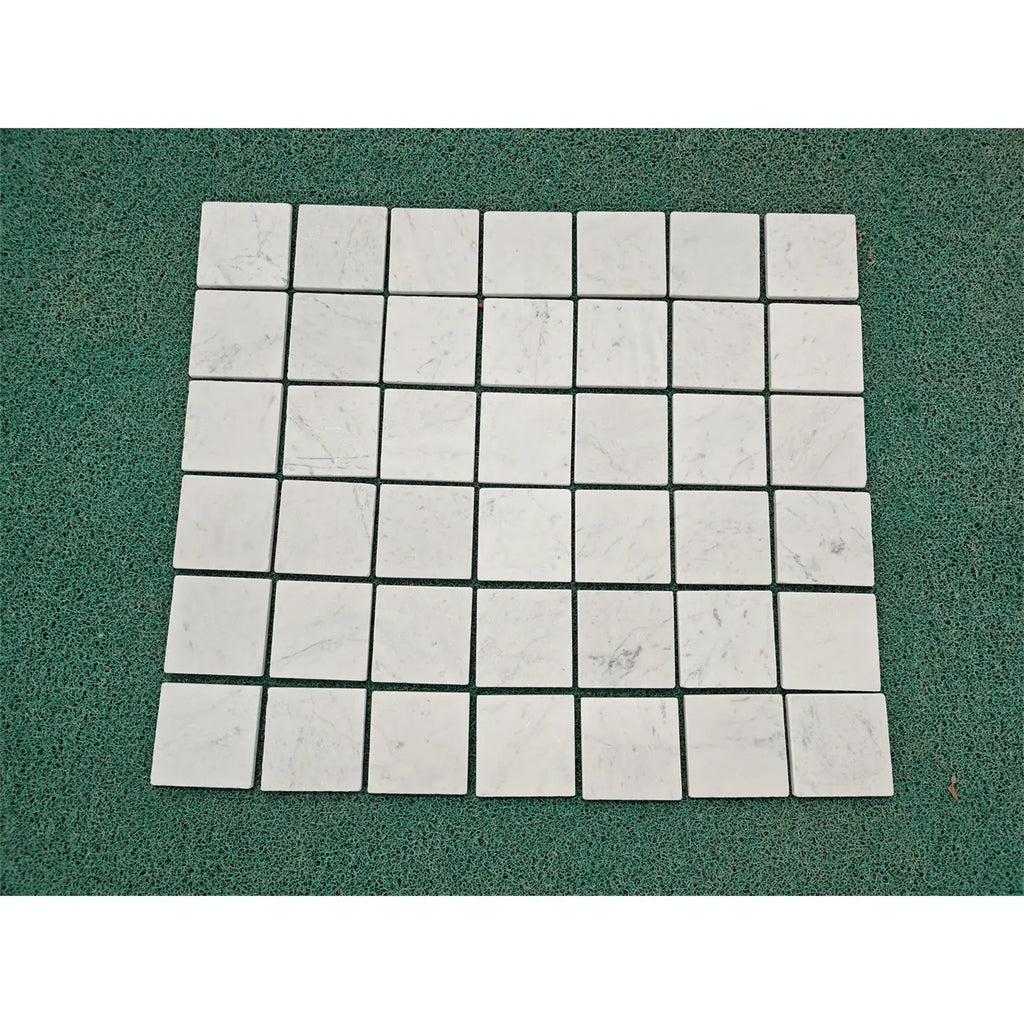 Carrara white marble 4x4 tumbled tiles with white marble mosaic and subtle gray veining arranged in a grid pattern