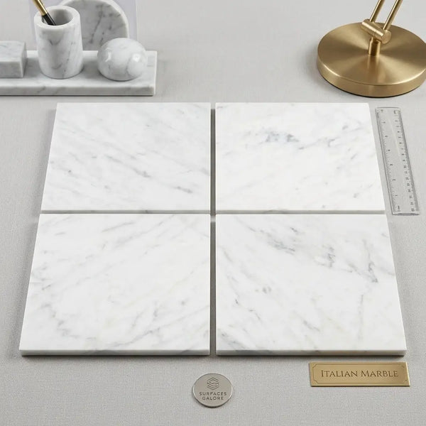 Four polished or honed 6x6 white Carrara marble tiles with subtle gray veining arranged in a grid pattern
