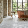Copper freestanding bathtub with polished reflective surface and classic rounded edges on carrara white penny-round mosaic marble tile