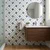 Modern round mirror with sleek silver frame paired with carrara white stanza black blue-gray mosaic marble tile polished or honed