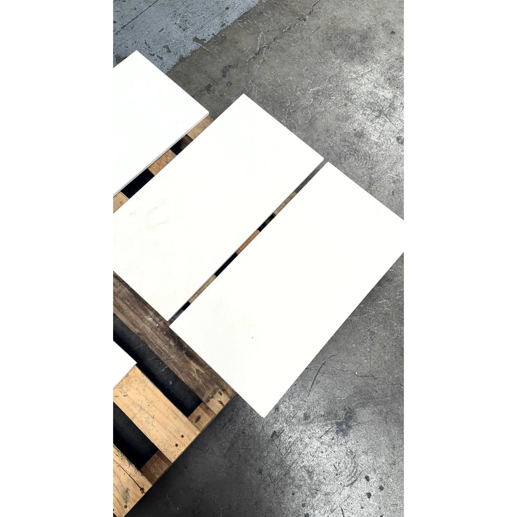 White rectangular ceramic tiles in champagne color resting on wooden pallet for lymra 12x24 limestone honed product