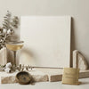 A minimalist white champagne limestone honed lymra 18x18 canvas leaning against a neutral wall with stone and metal accents