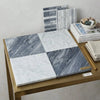 Gray and white checkerboard bardiglio and bianco carrara marble tile samples arranged on a gold-framed display board