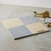 Square marble tile sample pad labeled surfaces palette featuring two-tone beige and gray veined checkerboard design