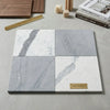 Set of four checkerboard marble tile samples in white and gray with natural veining on a neutral surface