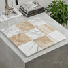 A square mosaic tile panel with alternating white calacatta gold and beige diano royal marble tiles in a grid pattern