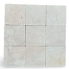 Light beige Crema Marfil 4x4 tumbled marble tiles with subtle veining patterns