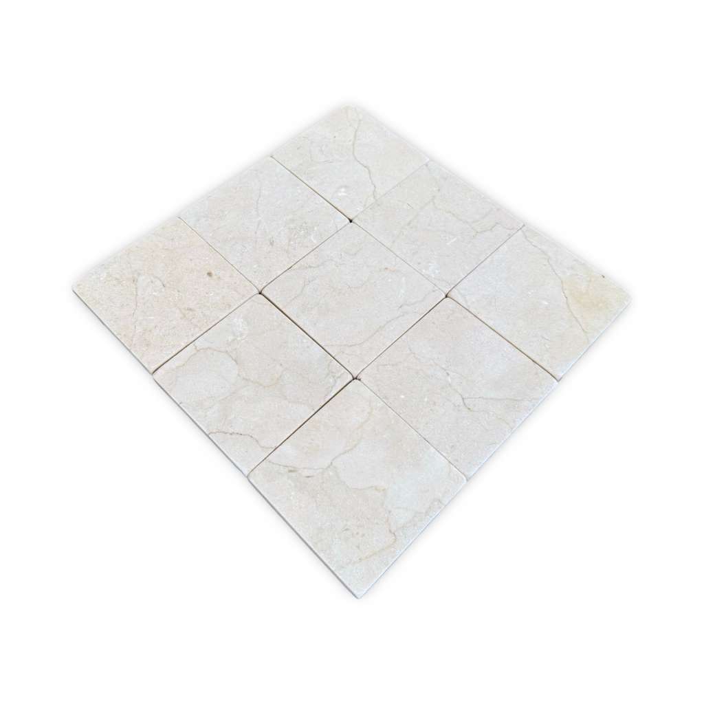 A grid of twelve light-colored Crema Marfil 4X4 Tumbled natural stone tiles with subtle variations