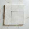 Crema Marfil 4X4 Tumbled marble tiles with subtle veining in a grid layout