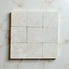 Crema Marfil 4X4 Tumbled marble tiles with subtle veining in a grid layout
