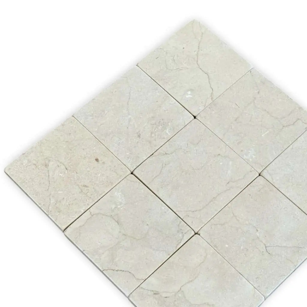 Light-colored square marble tiles with natural veining in Crema Marfil 4X4 Tumbled product