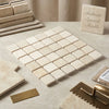 Beige crema marfil marble 2x2 mosaic tumbled tiles with subtle veining arranged in a grid pattern on mesh backing