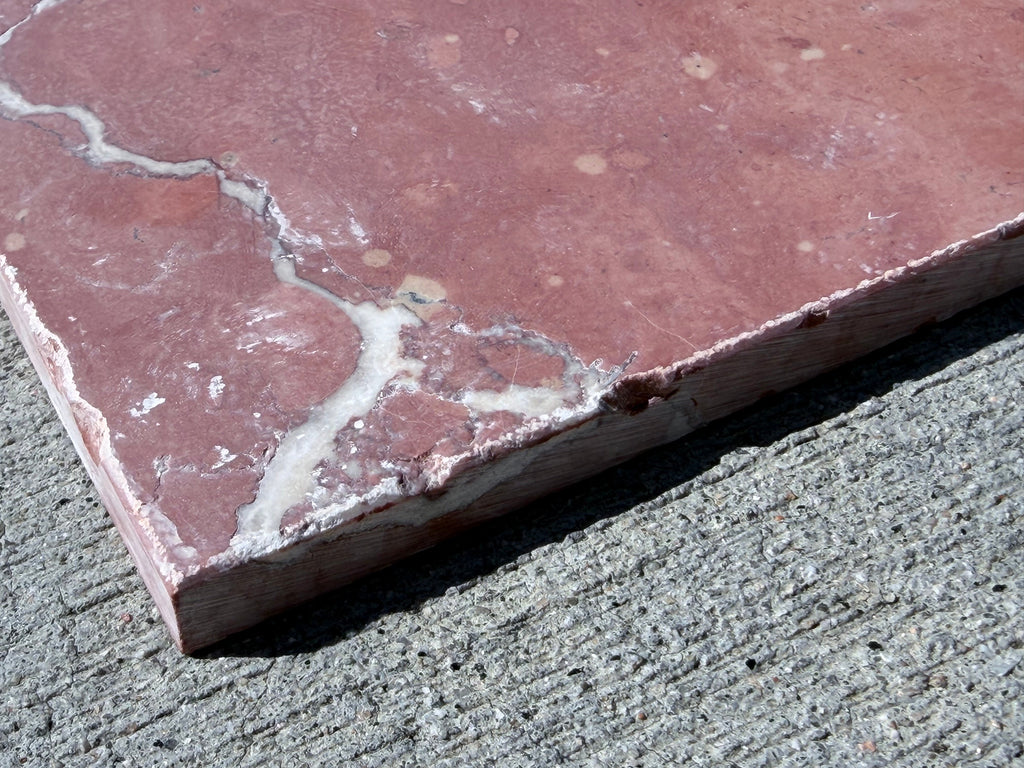 Crema Marrfil Rustic Modern Tumbled reddish-pink marble slab with white veining and chipped edge