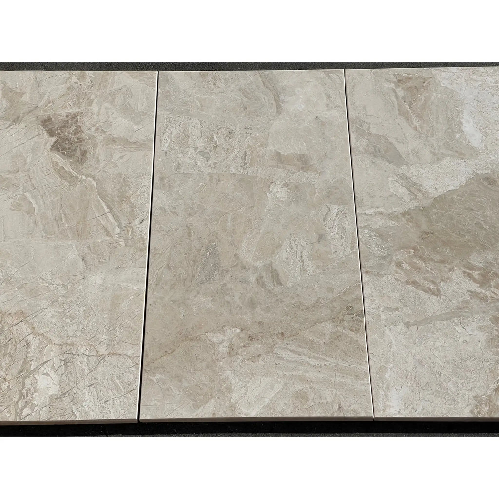 Three polished beige marble effect diano royal queen beige 12x24 tiles with subtle gray veining and glossy finish