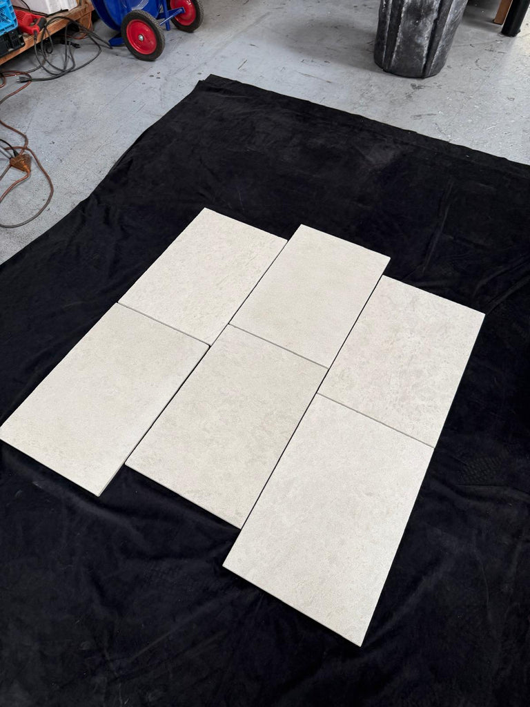 Six Dolce Crema 18X18 Limestone tiles with marbled texture on black fabric