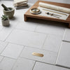 Gold-colored metal plaque with engraved text surfaces galore on dolce ivory 18x18 limestone tile floor